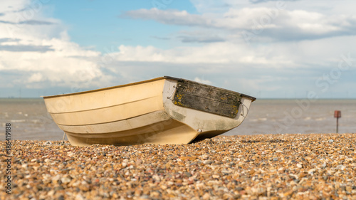 Clouds over a boat on the pebbles of Tankerton beach in Whitstable, Kent, England, UK photo