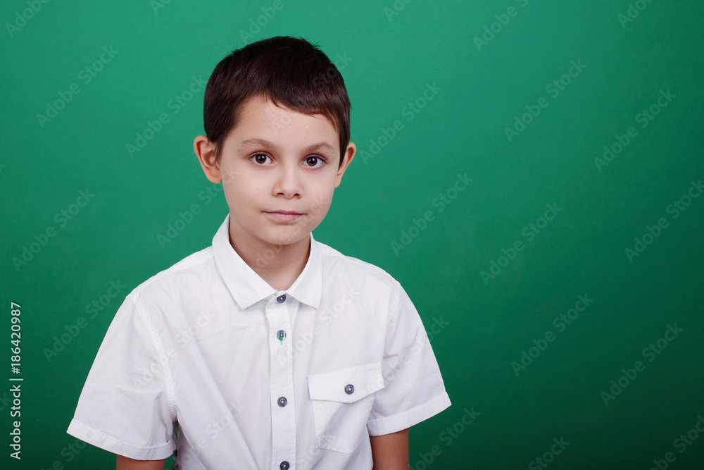 Boy in white shirt on green background, close-up portrait Boy in white shirt on green background, close-up portrait