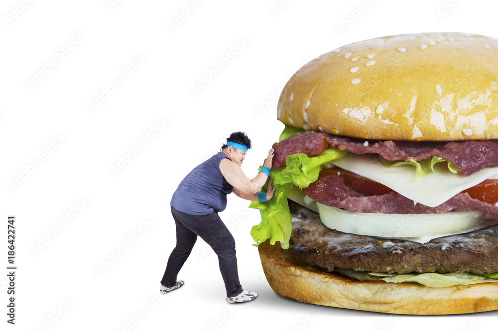 Overweight man pushing big burger Overweight man pushing big burger