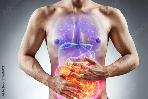 Man holding his stomach in pain. Photo of man with naked torso experience irritable bowel syndrome on grey background. Medical concept photo