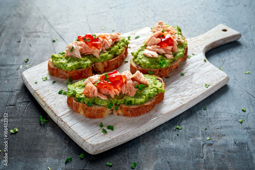 Homemade Toast sandwich with Salmon, Avocado and chilli jam on wihte wooden board. healthy food