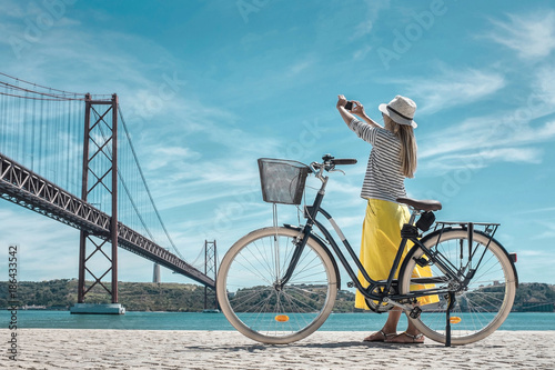 Blonde woman in summer hat and yellow skirt with her city bicycl photo