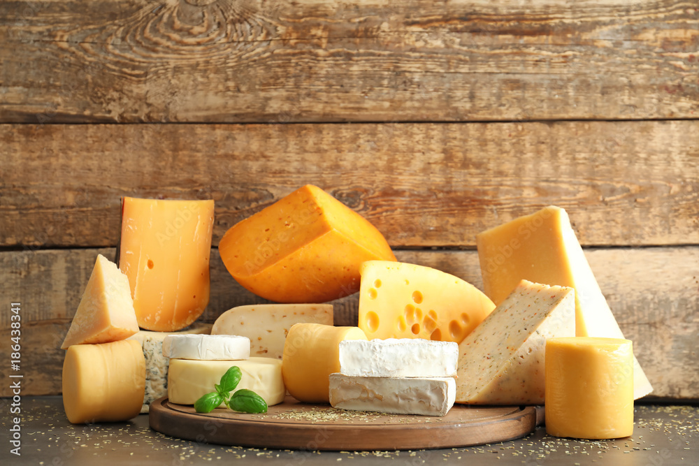 Fototapeta premium Wooden board with different kinds of delicious cheese on table