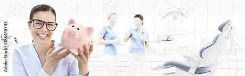 dental care savings concept, beautiful smiling woman with piggy bank on dentist clinic background with dentist's chair, web banner template