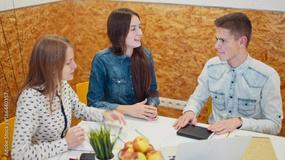 Three Young People are Working on Business Project in a Modern Office Room. Hot Discussion of Work Issues Three Young People are Working on Business Project in a Modern Office Room. Hot Discussion of Work Issues