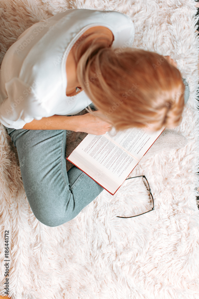 Beautiful blond caucasian woman reading an amusing book on a wh Beautiful blond caucasian woman reading an amusing book on a wh