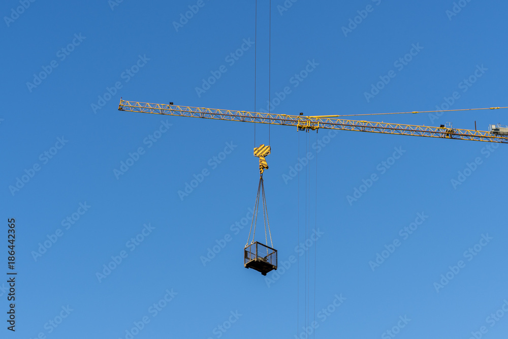 High-altitude crane lifts cargo, against the blue sky High-altitude crane lifts cargo, against the blue sky