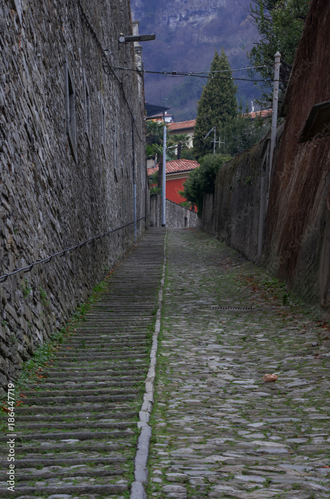 steep cobblestone alley with stairs of an ancient mountain village of Como Lake