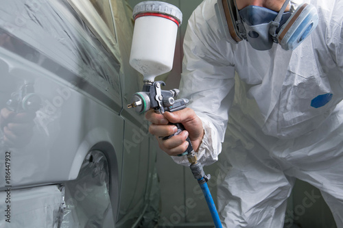 Painter spray gun in the hands of a painter.