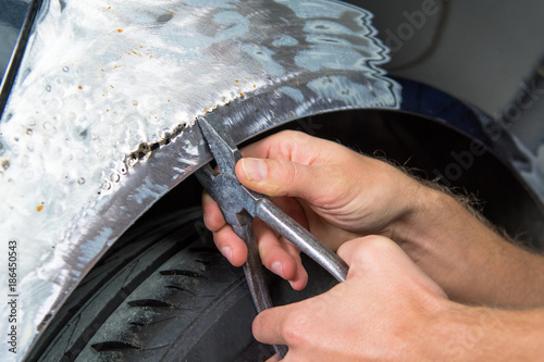 The bodyworker repair the car bodywork in the car shop.
