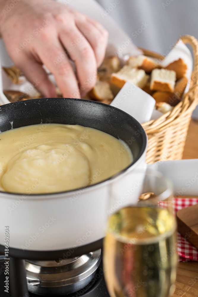 Mann isst Brot bei Käsefondue mit Fonduegabel Mann isst Brot bei Käsefondue mit Fonduegabel