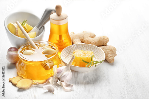 Composition with honey and garlic as natural cold remedies on white wooden background