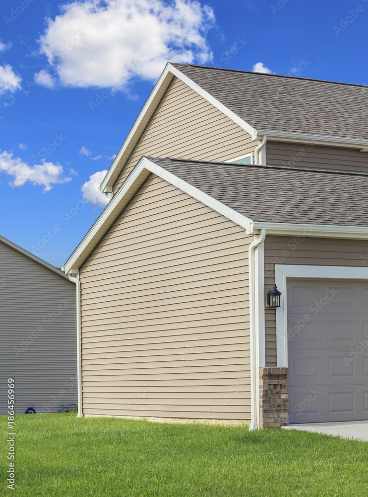 Contemporary two story home with tan vinyl siding, roof and gutters Contemporary two story home with tan vinyl siding, roof and gutters