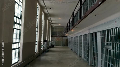 Hallway with prison cells on one side and windows to the outside on the other
