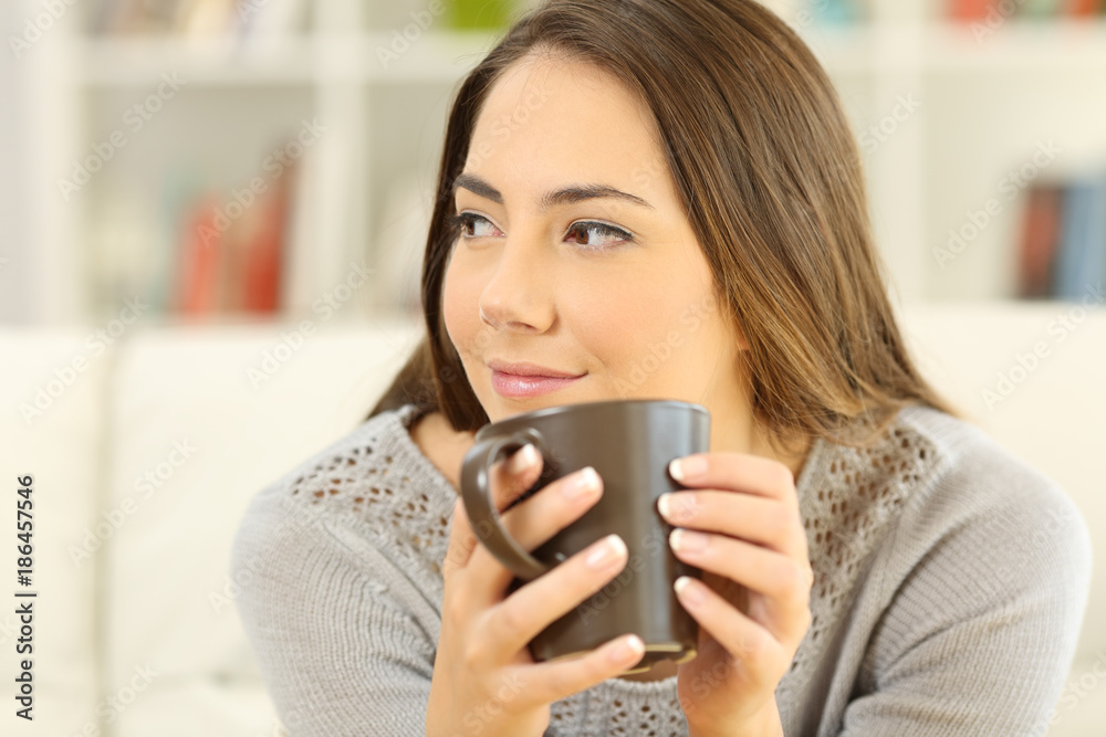 Pensive woman holding a coffee mug looking at side Pensive woman holding a coffee mug looking at side