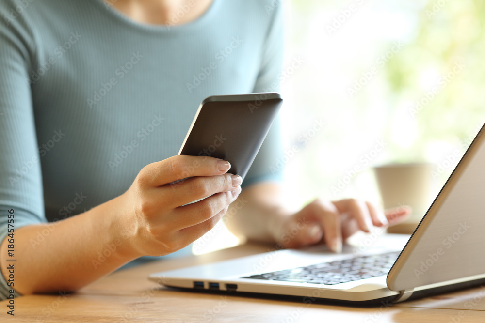 Girl hands using a smart phone and a laptop on a desk Girl hands using a smart phone and a laptop on a desk