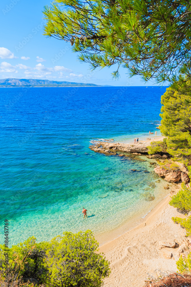 Fototapeta premium Unidentified man standing in water near famous Zlatni Rat beach in Bol town, Brac island, Croatia