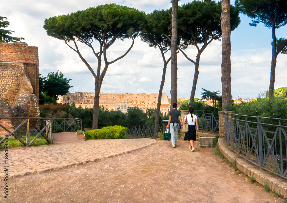 Couple walking on scenic Palatine Hill overlooking the Colosseum in Rome, Italy