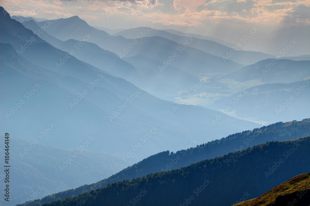 Blue sunlit silhouettes of ridges and slopes at summer sunset, Val Pusteria Pustertal valley Sesto Braies Dolomiti Sextner Pragser Dolomiten, Dobbiaco Toblach village Bolzano Alto Adige Sudtirol Italy