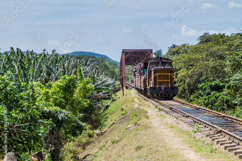 GUACHINANGO, CUBA - FEB 9, 2016: Local train crossing a bridge over Ay river in Valle de los Ingenios valley near Trinidad, Cuba