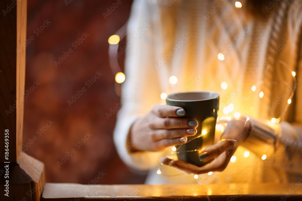 Young woman relaxing while drinking tea in living room on winter day