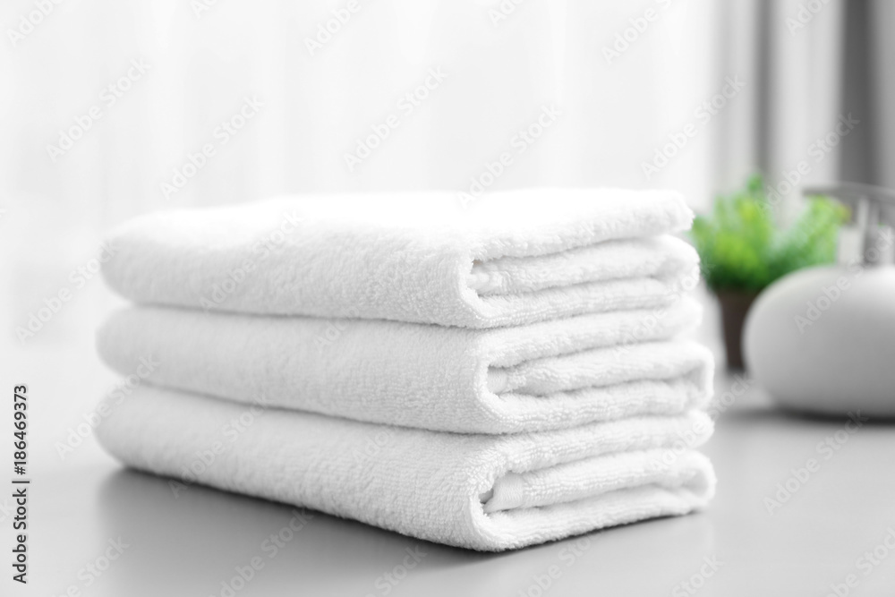 Stack of white clean towels on table in bathroom - obrazy, fototapety, plakaty 