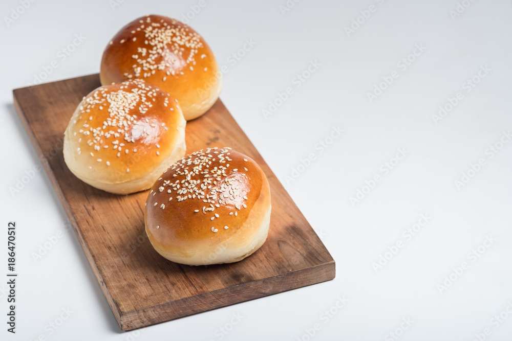 Tasty buns with sesame on oven-tray, on wooden background. Tasty buns with sesame on oven-tray, on wooden background.