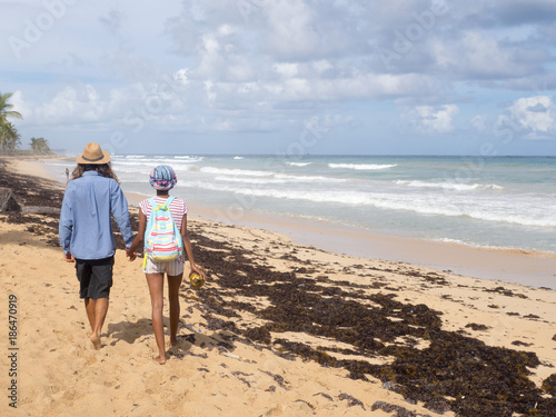 A girl and a man are walking along the beach.