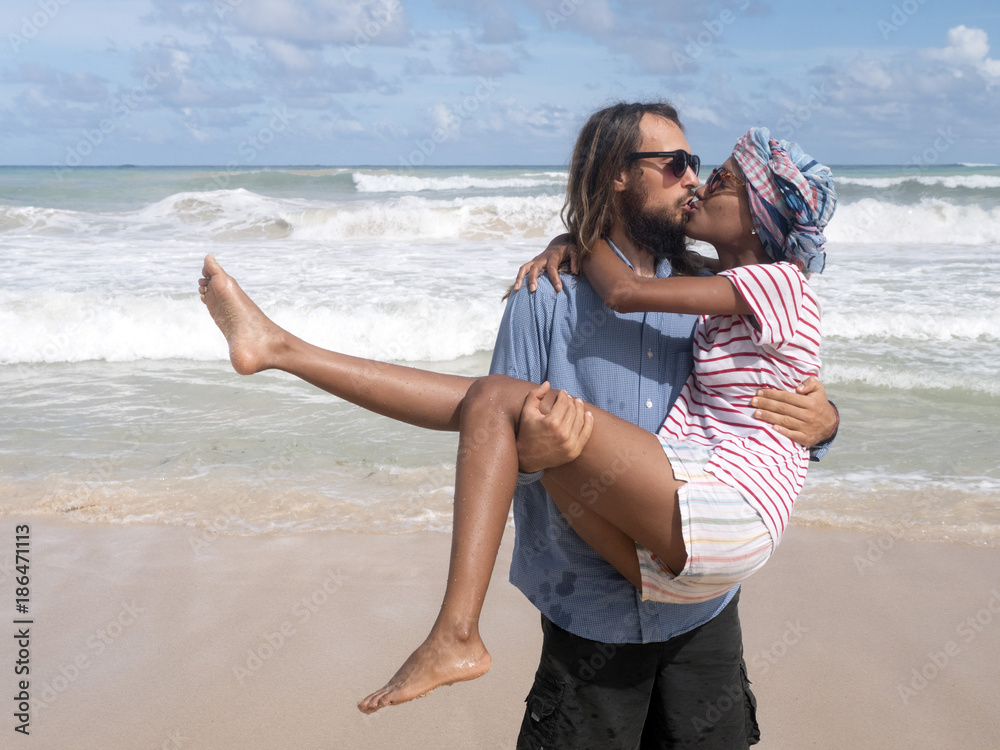 A girl and a man are kissing on the beach. European and African American