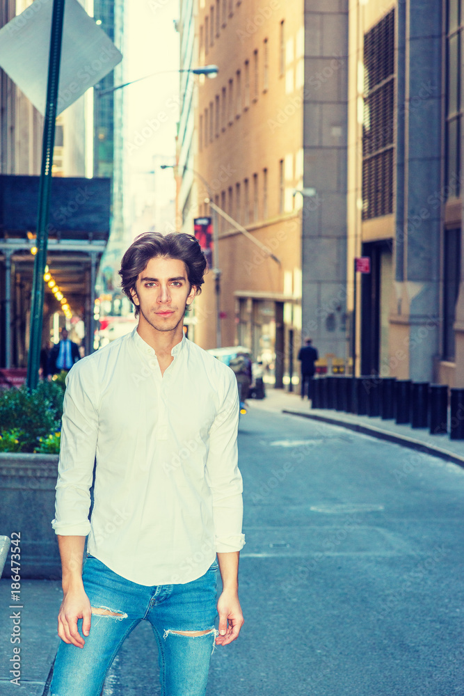 City life. Young handsome man wearing long sleeve white shirt, blue  destroyed jeans, standing on narrow vintage street in New York, looking,  waiting. Filtered effect. Stock Photo | Adobe Stock