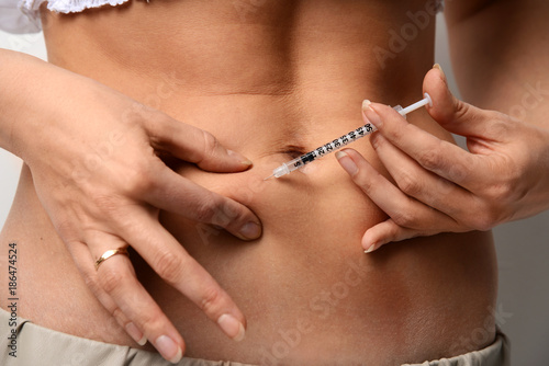 Woman make medical diabetes insulin syringe injection shot into abdomen