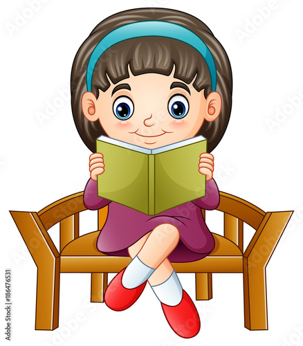 Little girl sitting on a chair reading a book