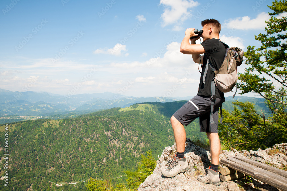 active Young man looking a mountain landscape with Binoculars