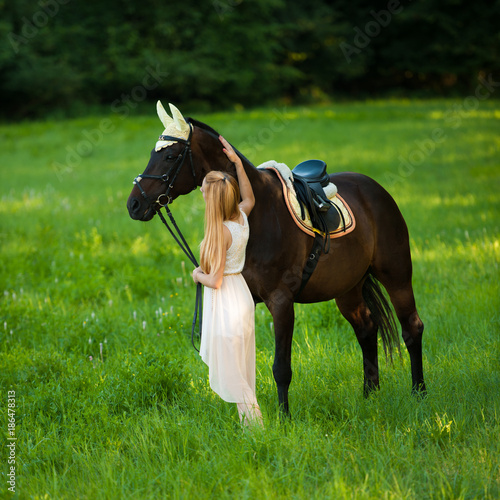 Beautiful young woman with horse outdoor on a walk in nature