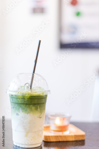 Iced Green tea matcha latte on wooden table in coffee shop.  Matcha is finely ground powder of specially grown and processed green tea leaves.