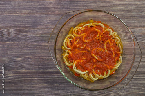  Squid rings with vegetables and tomato sauce in an ovenproof dish. The view from the top. Copy-space 