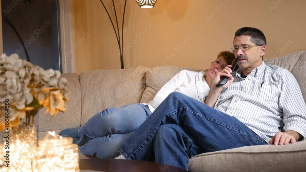 Man uses Voice Activated remote control while on couch watching TV with wife