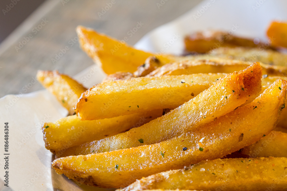 Hot, fresh, spicy french fries on baking paper. Closeup Hot, fresh, spicy french fries on baking paper. Closeup