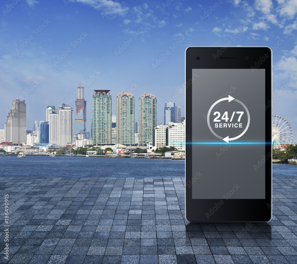 24 hours service icon on modern smart phone screen on stone tile floor over city tower, river and blue sky, Full time service concept 24 hours service icon on modern smart phone screen on stone tile floor over city tower, river and blue sky, Full time service concept
