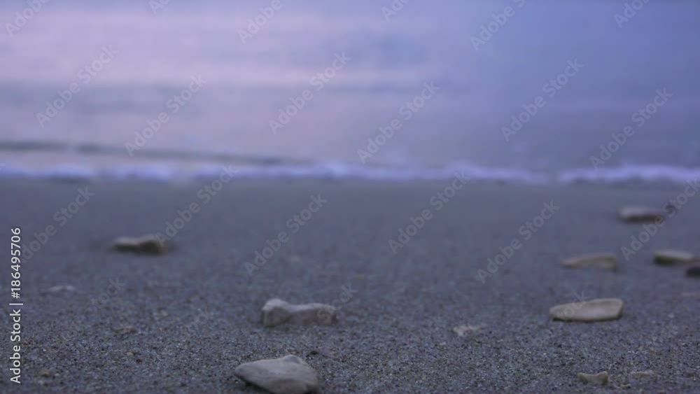 Sea wave with bubbles hits the sand beach with pebbles in the evening Sea wave with bubbles hits the sand beach with pebbles in the evening