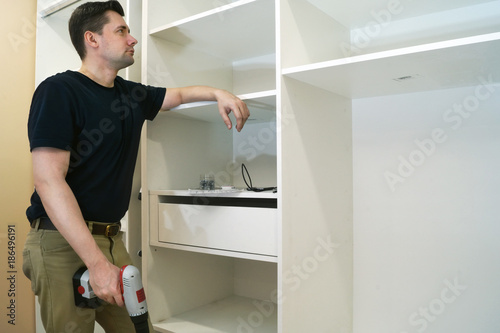 Repair man looking at cupboard or wardrobe. Installation of furniture.