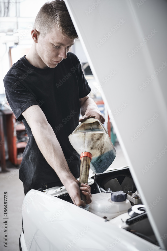 Young mechanic repair a car at a garage