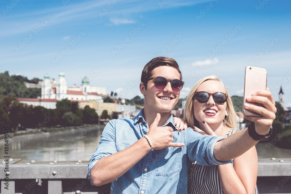 Junges Touristenpärchen macht Selfie mit Smartphone in Passau