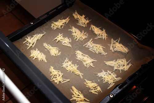 Making parmesan chips, grated cheese in heaps on a baking tray ready for baking in the oven