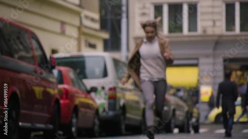 A woman sprints down a paved road in a street in an urban area - slow motion - view from the ground - blurred