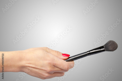 Woman hand holding cosmetic tool isolated on color background