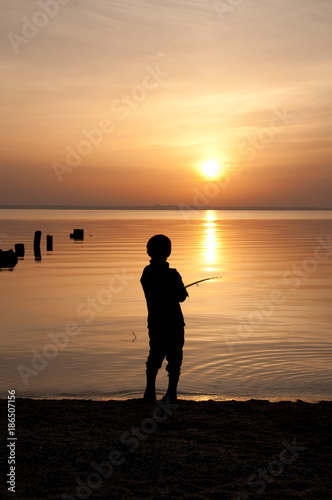Silhouette of a fisherman on a sunset background
