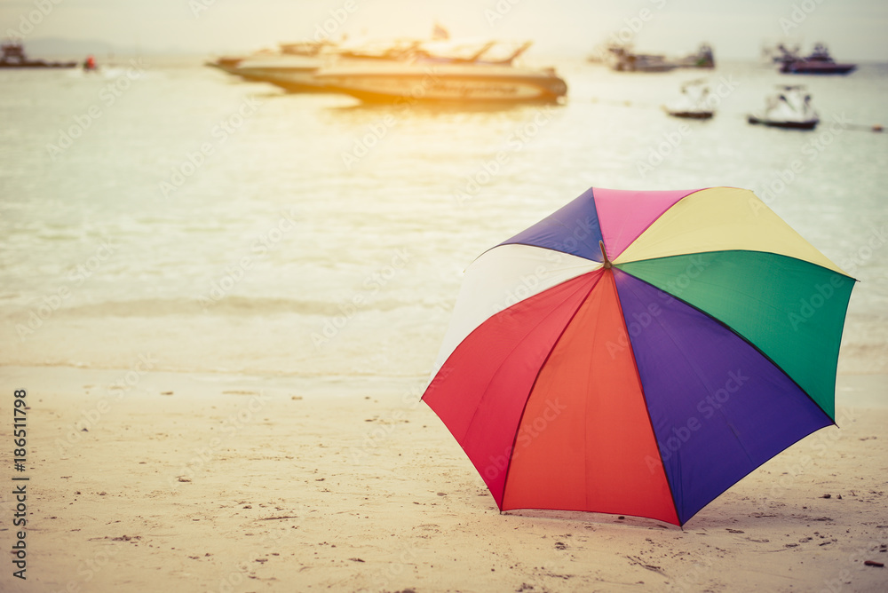 Rainbow color umbrella on beach. Holiday and Forgotten Object concept. Outdoor and Memorial concept. Sand and sea theme.