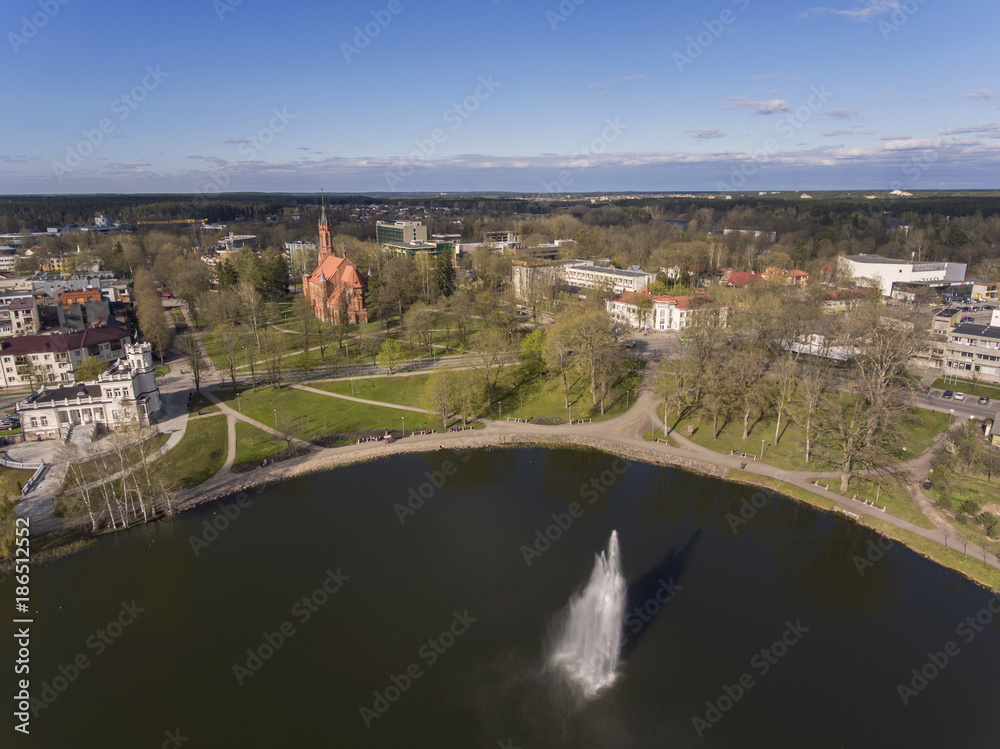 Aerial view over Druskininkai city lake fountain with city church and museum in the background, Lithuania. During spring time.