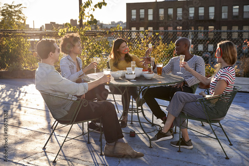 Friends talking on a New York rooftop raise glasses